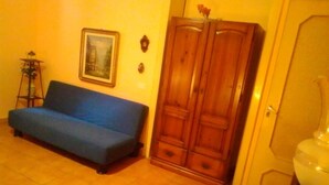 A living room with a blue sofa, wooden wardrobe, and a framed picture on the wall. - Palermo Centrale (Palermo)