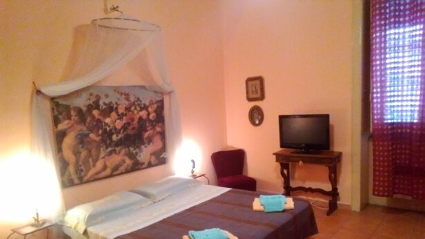 A room with a bed, a chair, a television, and a painting on the wall. - Palermo Centrale (Palermo)