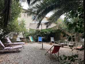 An outdoor seating area with lounge chairs, a table, and a shaded umbrella. - Country house with a lot of character in Corneilla del Vercol (CORNEILLA DEL VERCOL)