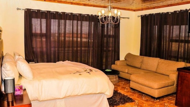 Habitación de hotel con cama, sofá, candelabro y cortinas.