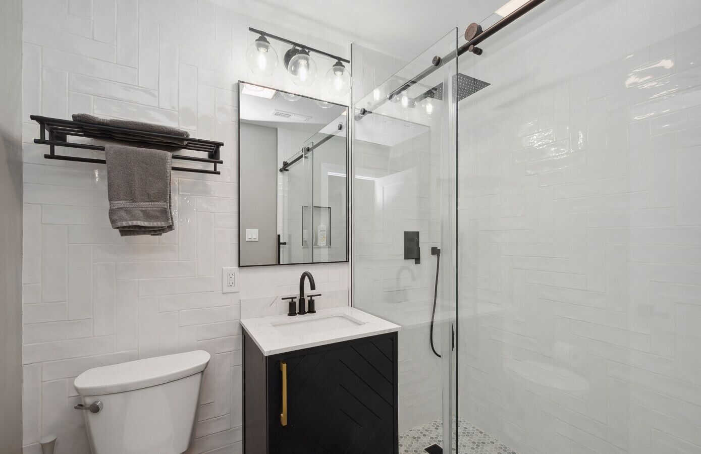 Une salle de bain moderne équipée de toilettes, d’un lavabo et d’une douche à parois de verre.