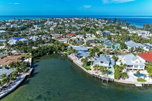 An aerial view of a coastal residential area with houses, a marina, and a clear view of the ocean. - Crescent Palms north end Ami, 2 King suites (Anna Maria)