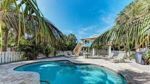 Ein Pool mit gewölbter Kante, umgeben von einer Holzterrasse und Palmen.