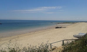 A beach with clear blue water, sandy shore, and a few boats. - Cotentin country house (CRASVILLE)