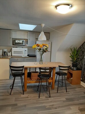 Enjoy meals at the dining table with appliances and a vase with fresh flowers.