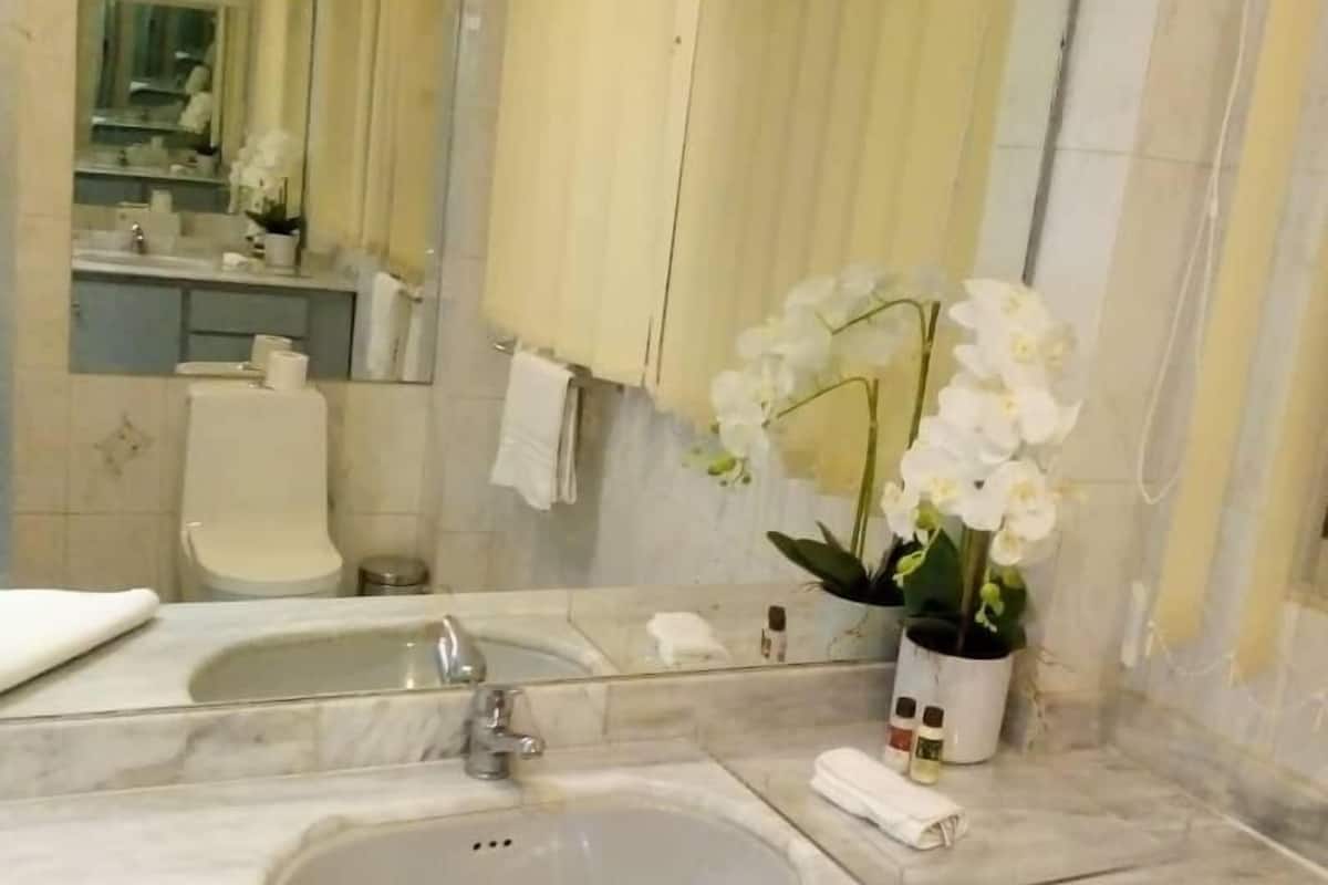 A bathroom with a marble sink, a mirror, a toilet, and a shower area.