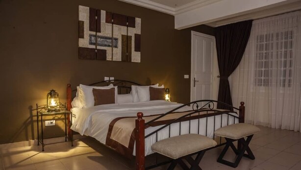 Ein Schlafzimmer mit einem Bett, Nachttischen, einer Bank und einem Wandbild.