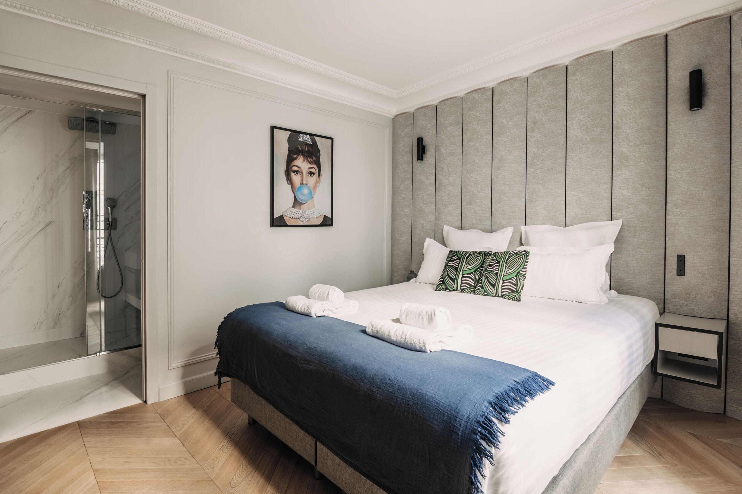 Un dormitorio moderno con una cama grande, una ducha y un cuadro en la pared.