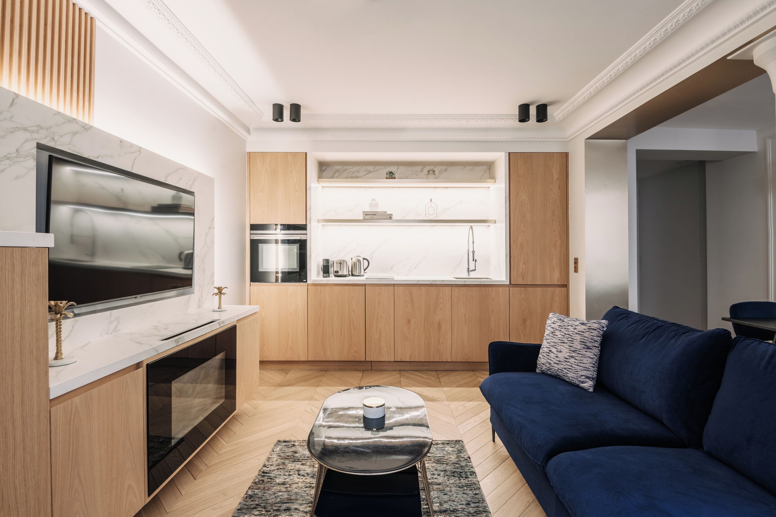 Un salon moderne avec un téléviseur à écran plat, un canapé bleu et une table basse.