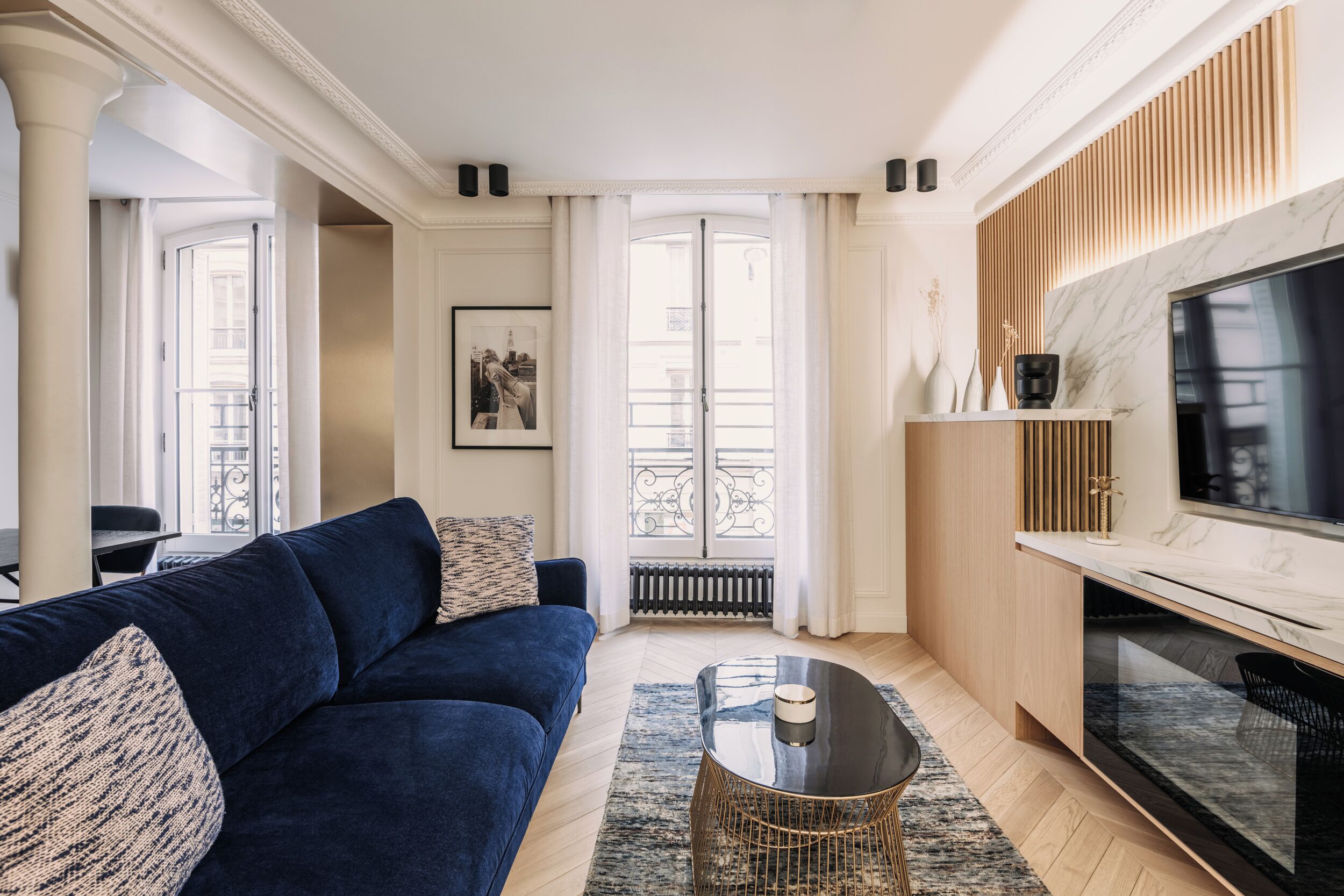 A modern living room with a blue sofa, a coffee table, and a TV.