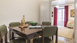 A dining room with a wooden table, six chairs, a green bowl, a bottle, and a book.