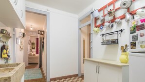 A kitchen with a checkered floor, white cabinets, and various kitchen utensils hanging on the wall.