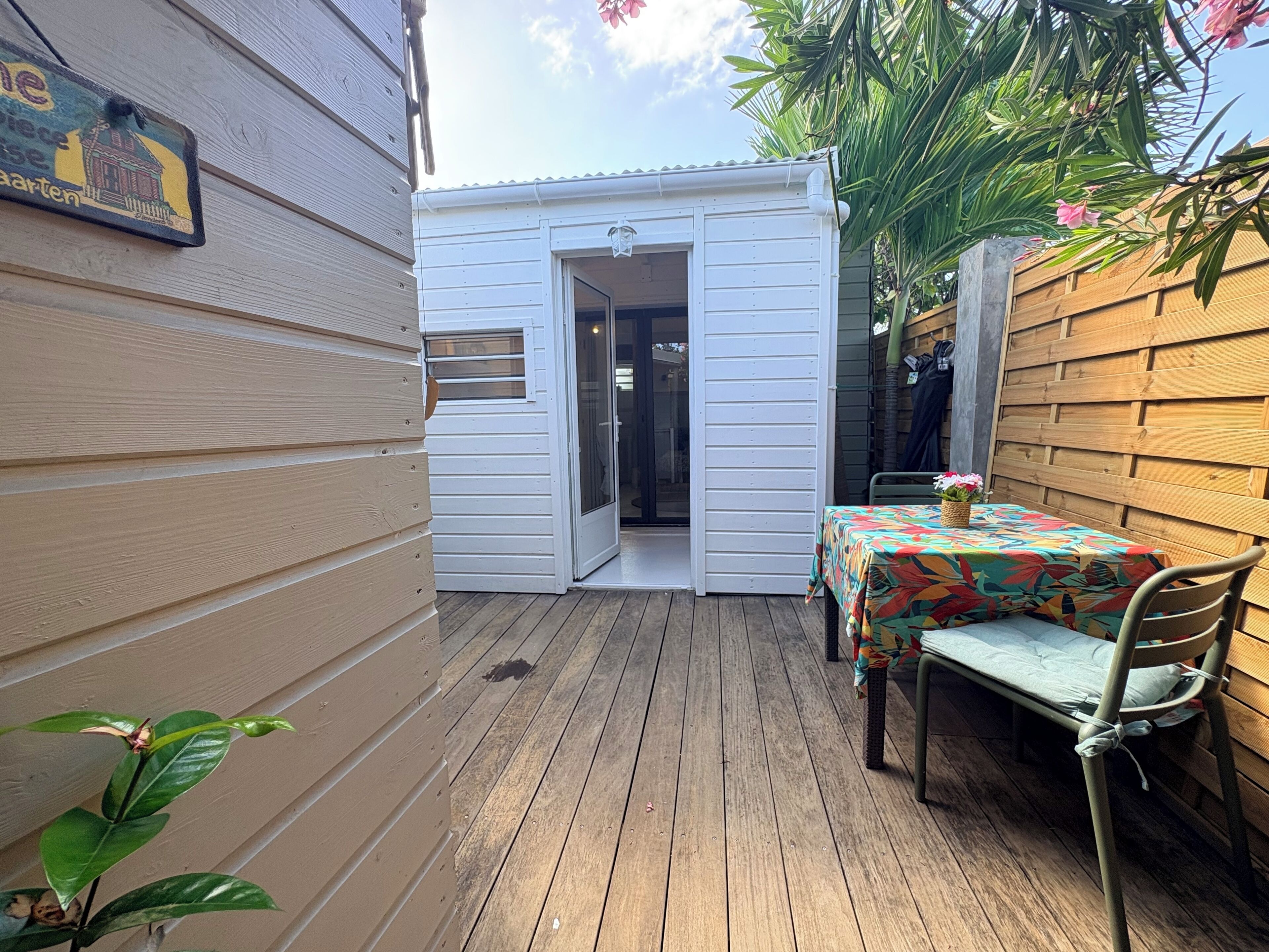 Um deck de madeira com mesa e cadeiras, uma porta de correr e um cercado de madeira.