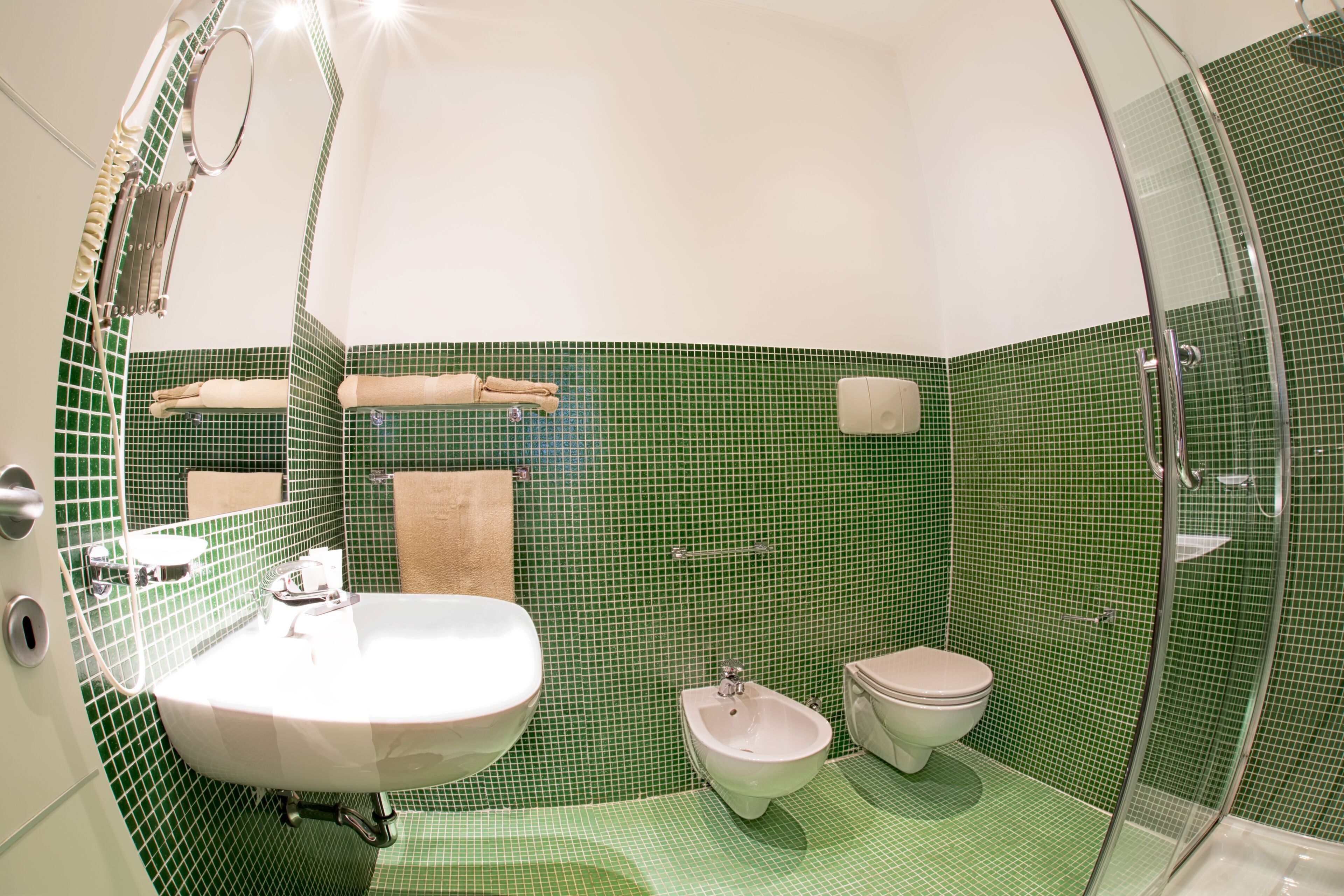 Un baño con lavamanos, bidé, inodoro y cabina de ducha de cristal.