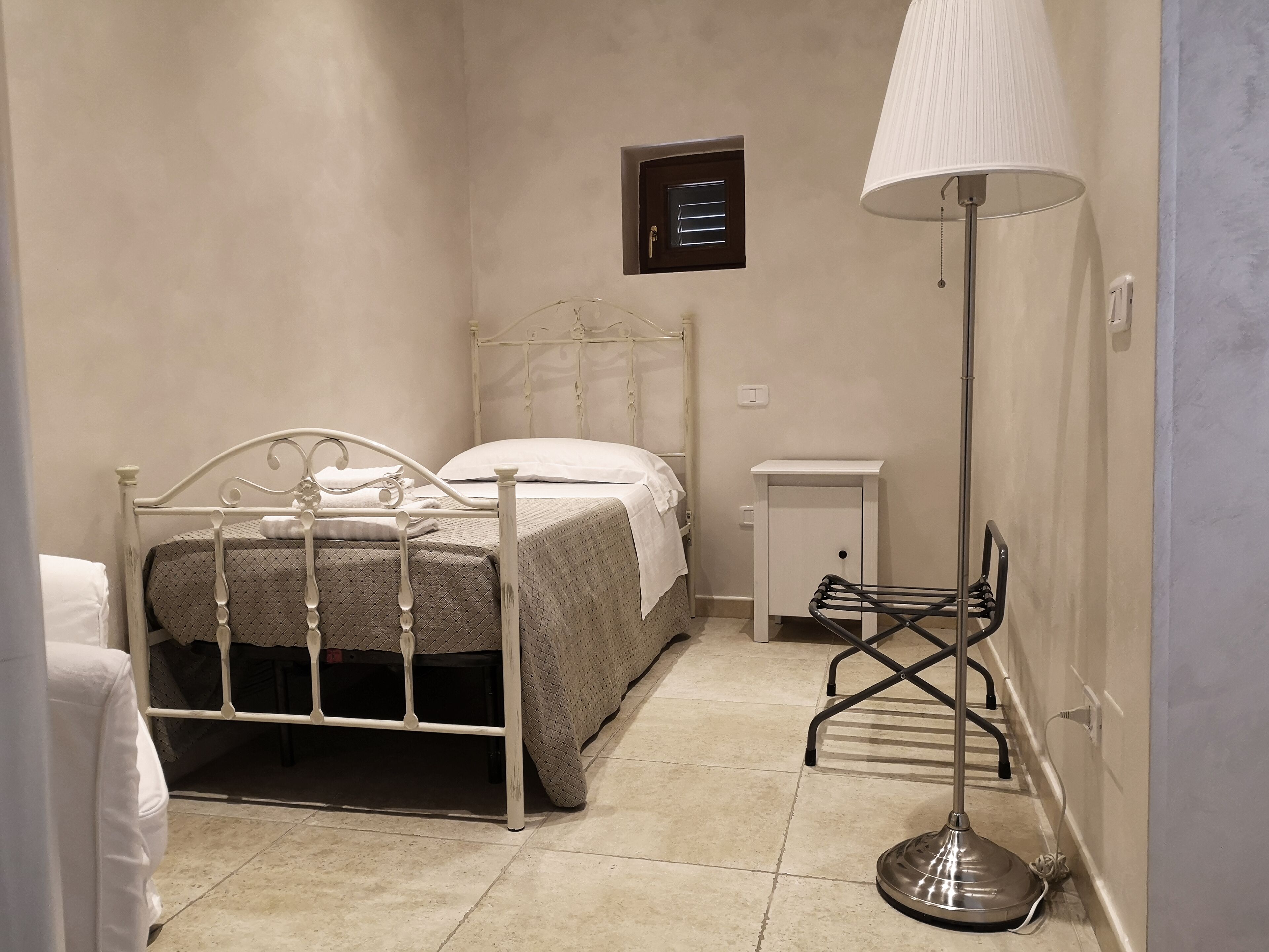A bedroom with a bed, bedside table, lamp, and a small cabinet.