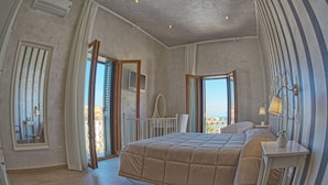 A bedroom with a large bed, a balcony with a view, and a bathroom with a shower and toilet. - Relais La Pretura (Vieste)