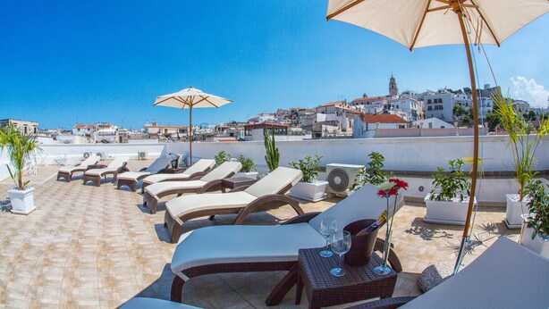 A rooftop lounge area with sun loungers, umbrellas, and potted plants. - Relais La Pretura (Vieste)