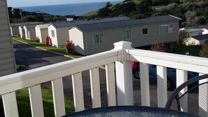 En balkon med et bord og stole, der giver udsigt over en række ferieboliger med havudsigt.