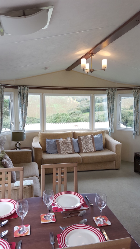 A dining area with a table set for four, a sofa, and a window with curtains.