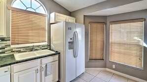Una cocina con refrigerador integrado, un lavamanos y una ventana con persianas.