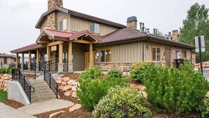 A two-story house with a stone facade, a covered porch, and a landscaped front yard with shrubs and a small tree. - Convenient Park City Condo (Park City)