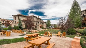 A courtyard with picnic tables and chairs, surrounded by stone buildings and greenery. - Convenient Park City Condo (Park City)