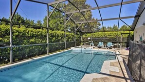 A covered outdoor swimming pool with clear blue water, surrounded by a metal fence and shaded by a canopy. - Achieve your Magical Vacation! 12 Mins to Disney! (Kissimmee)