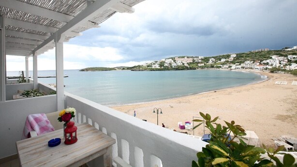 A balcony with a view of a beach and houses in the background. - Bella Vista Design Studios (Andros)