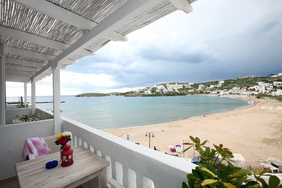 A balcony with a view of a beach and houses in the background.