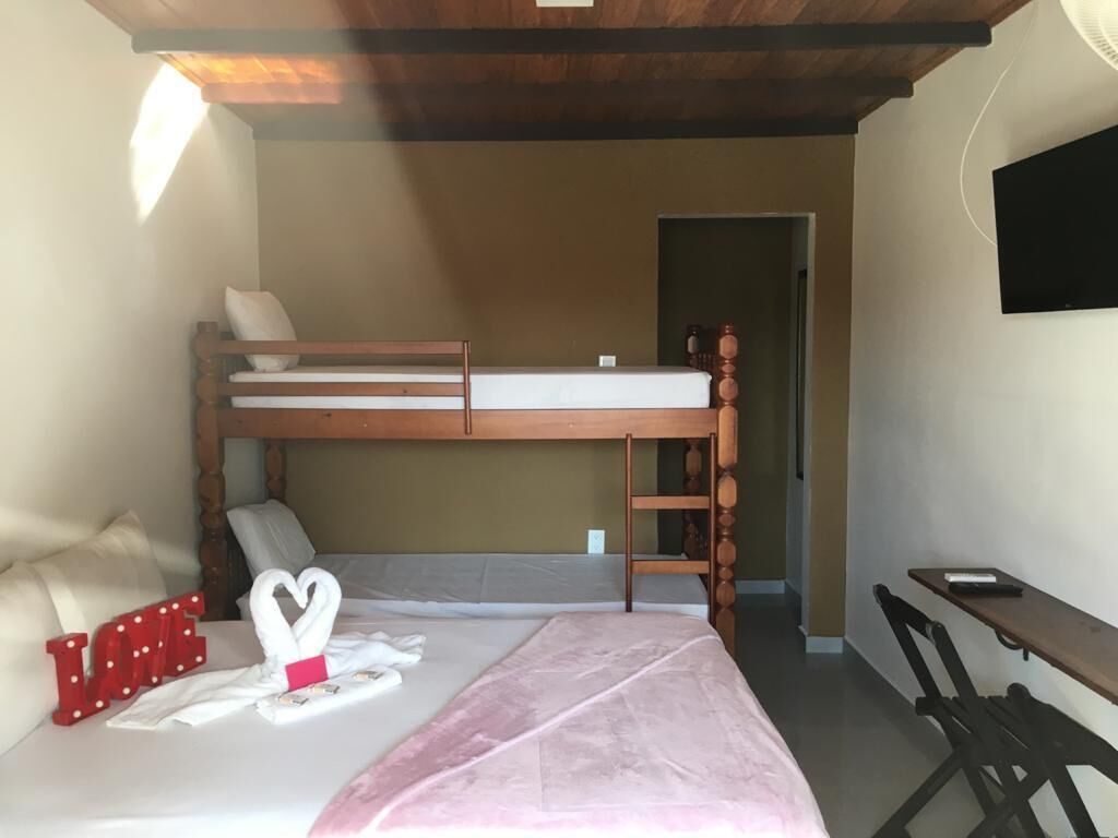 Ein Schlafzimmer mit einem Etagenbett, einem Schreibtisch und einem Bett mit einer rosa Tagesdecke.
