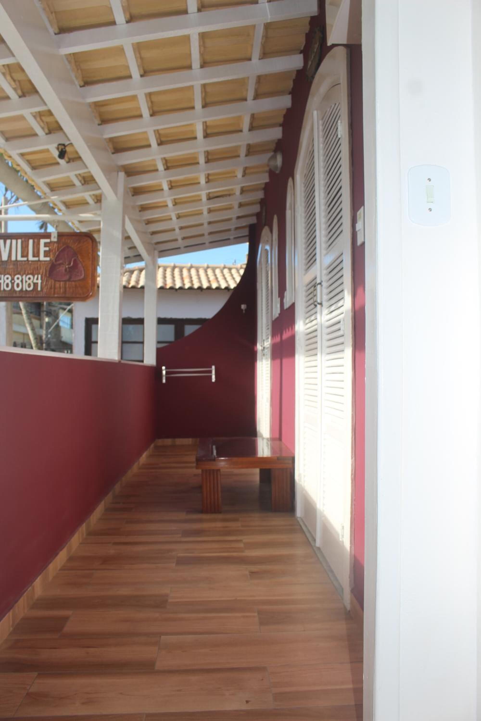 Un corredor cubierto con suelo de madera, un banco y un cartel con el nombre 'VILLE'.