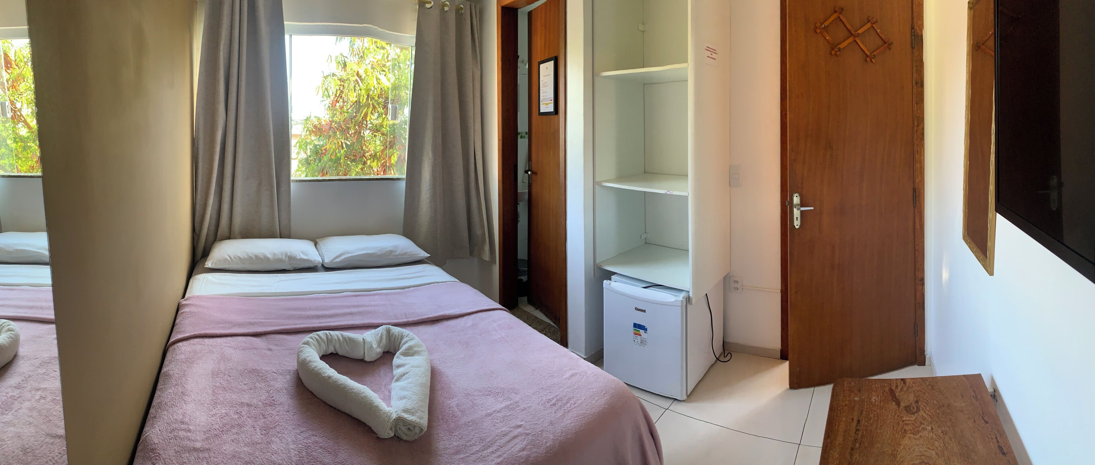 Habitación de hotel con dos camas, un refrigerador pequeño y una puerta de madera.