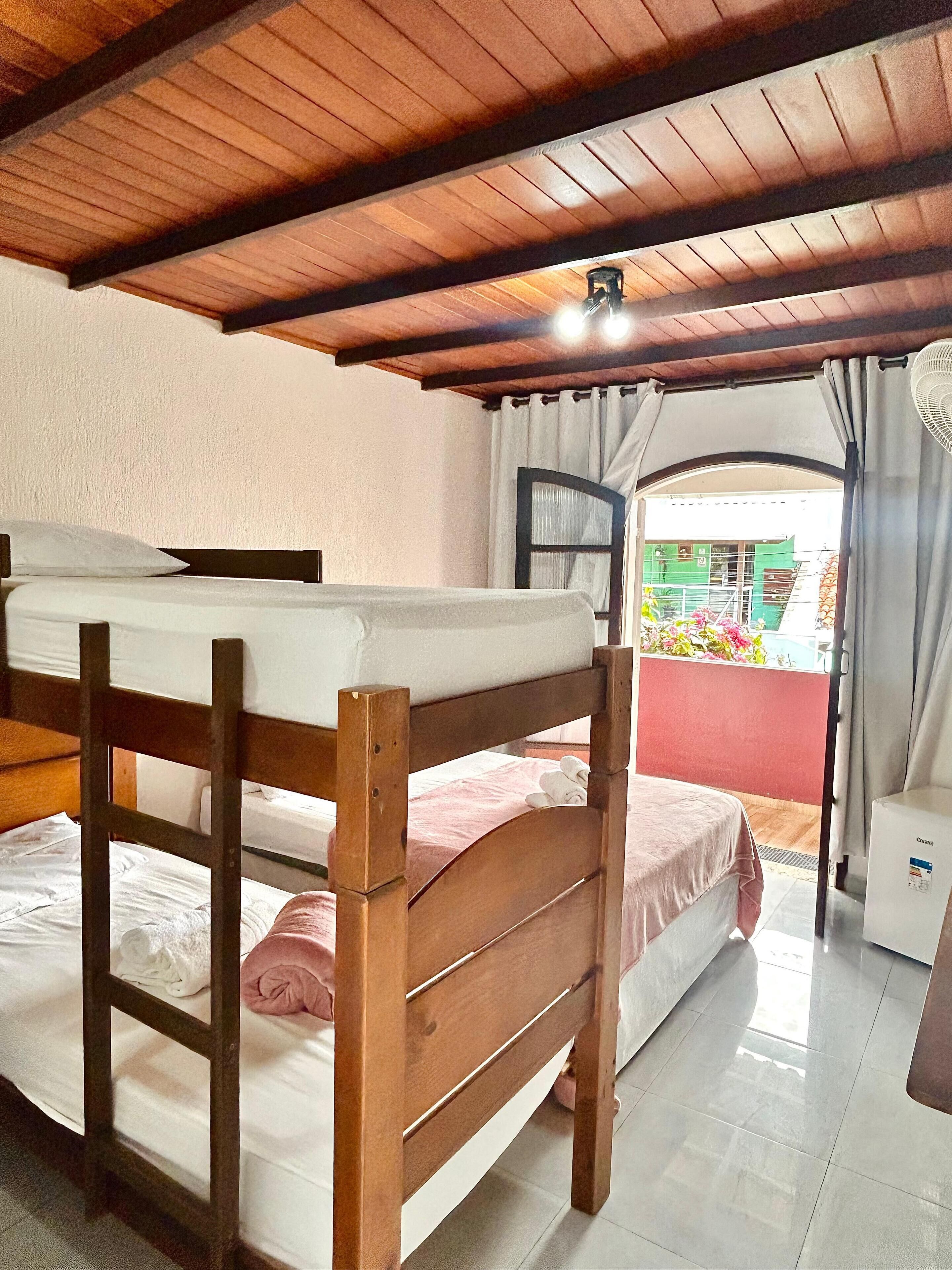 A room with two bunk beds, a ceiling fan, and a window with curtains.