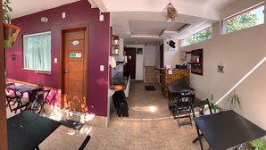 A hotel lobby with a reception desk, a staircase, and a dining area with tables and chairs. - Pousada Bougainville Suites (Arraial do Cabo)