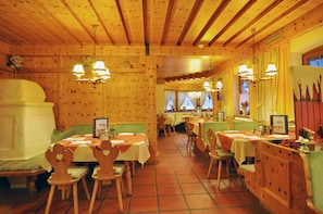 A restaurant with wooden interiors, multiple tables, and chairs. - Kaiserhotel Kitzbühler Alpen (Oberndorf in Tirol)