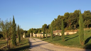 A gravel path leading to a building with a sloped roof, surrounded by trees and a clear sky.