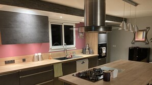 Une cuisine moderne avec des meubles de couleur sombre, un plan de travail en bois, une cuisinière à gaz et une hotte en acier inoxydable.
