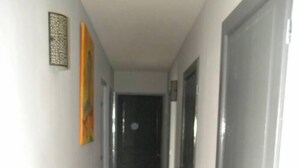 Un couloir étroit avec un plancher en bois, des murs blancs et des portes fermées de chaque côté.