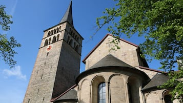 A church with a tall tower and a smaller adjacent building, both featuring arched windows and stone construction.