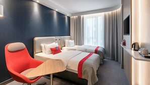 A hotel room with two beds, a red armchair, a bedside table, and a TV. - Holiday Inn Express Sindelfingen by IHG (Sindelfingen)