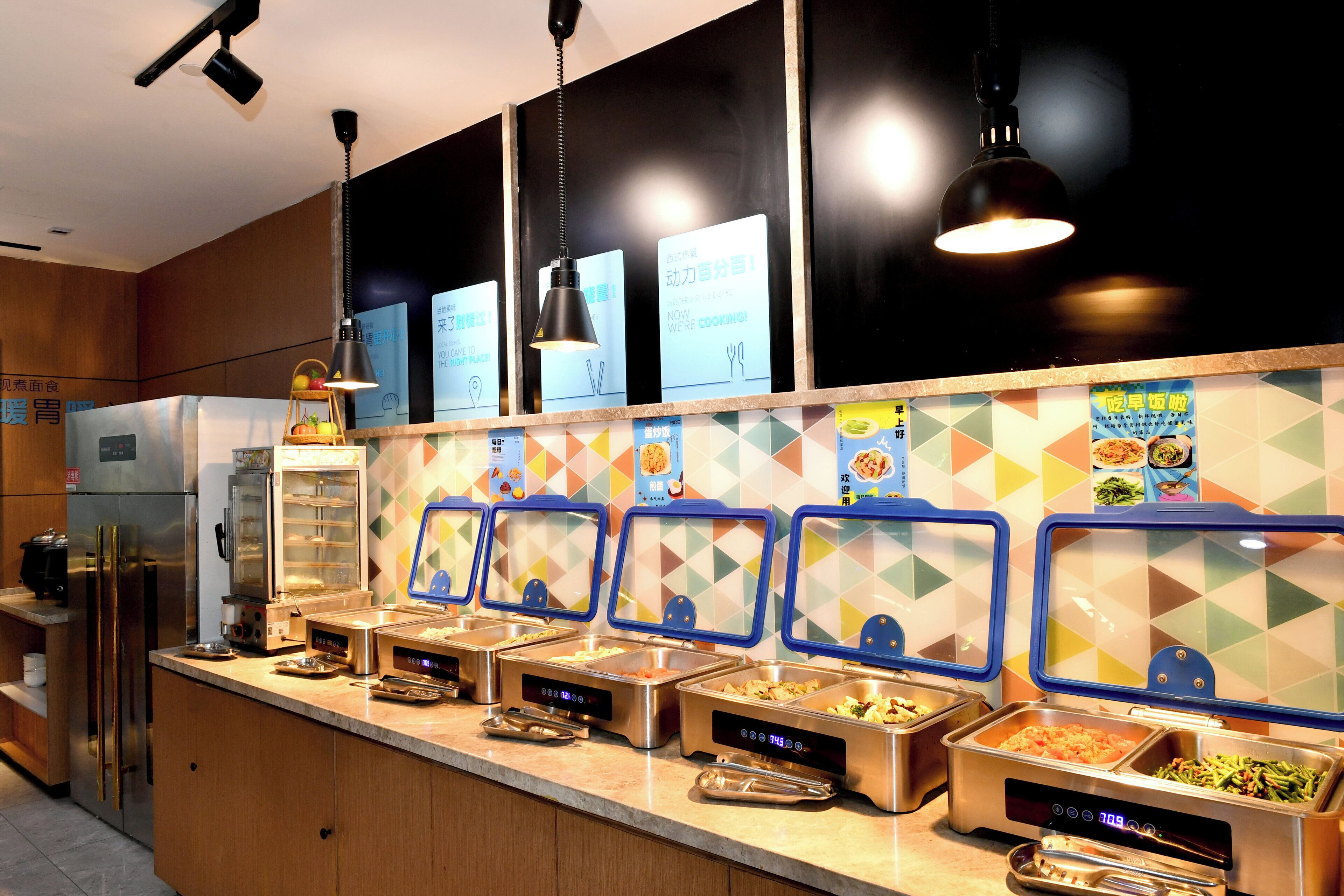 A buffet area with multiple food dispensers, a refrigerator, and a microwave.