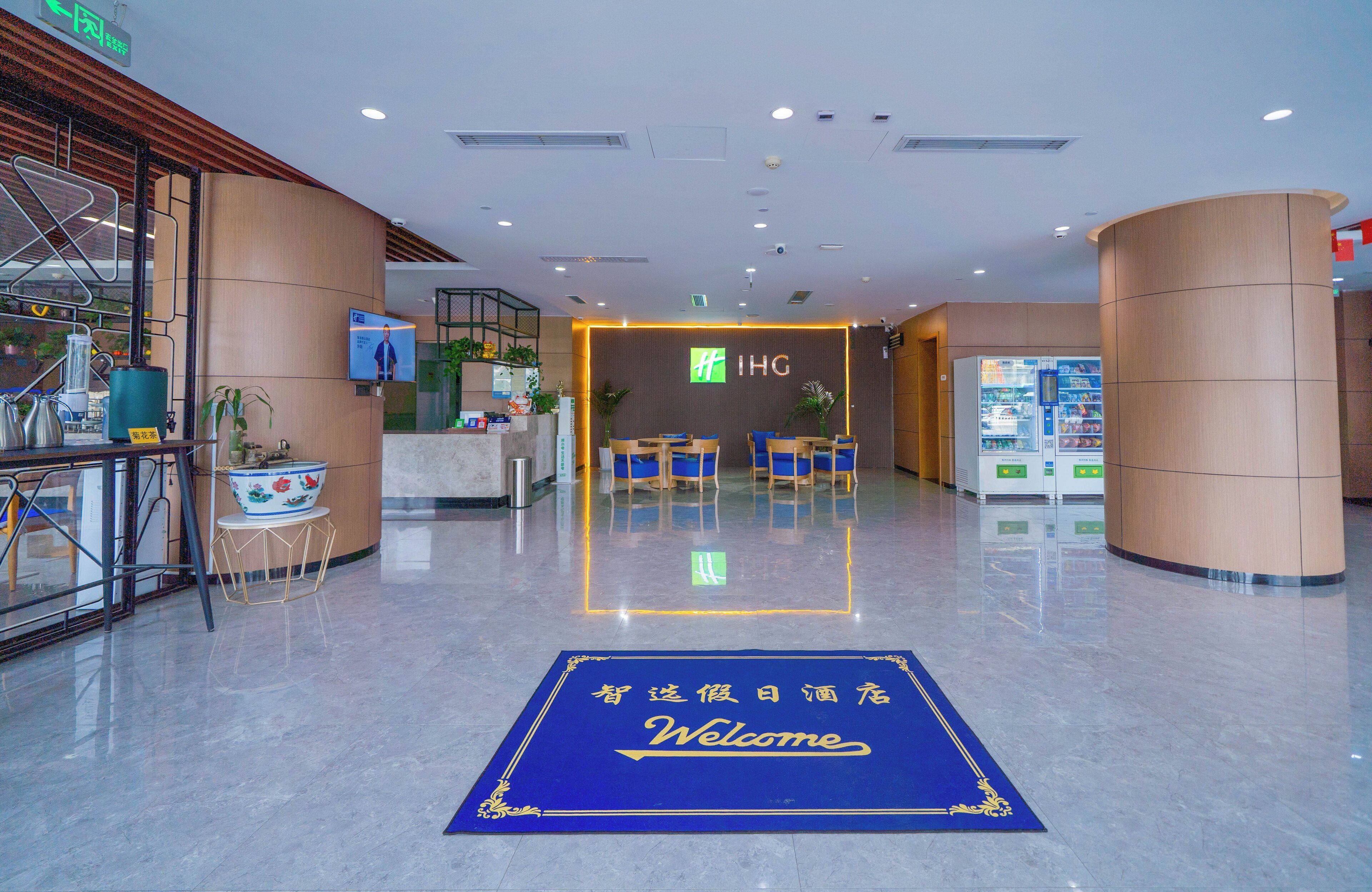 Un vestíbulo de hotel con mostrador de recepción, zona de estar y felpudo de bienvenida.