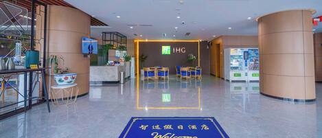 Un vestíbulo de hotel con mostrador de recepción, zona de estar y felpudo de bienvenida.
