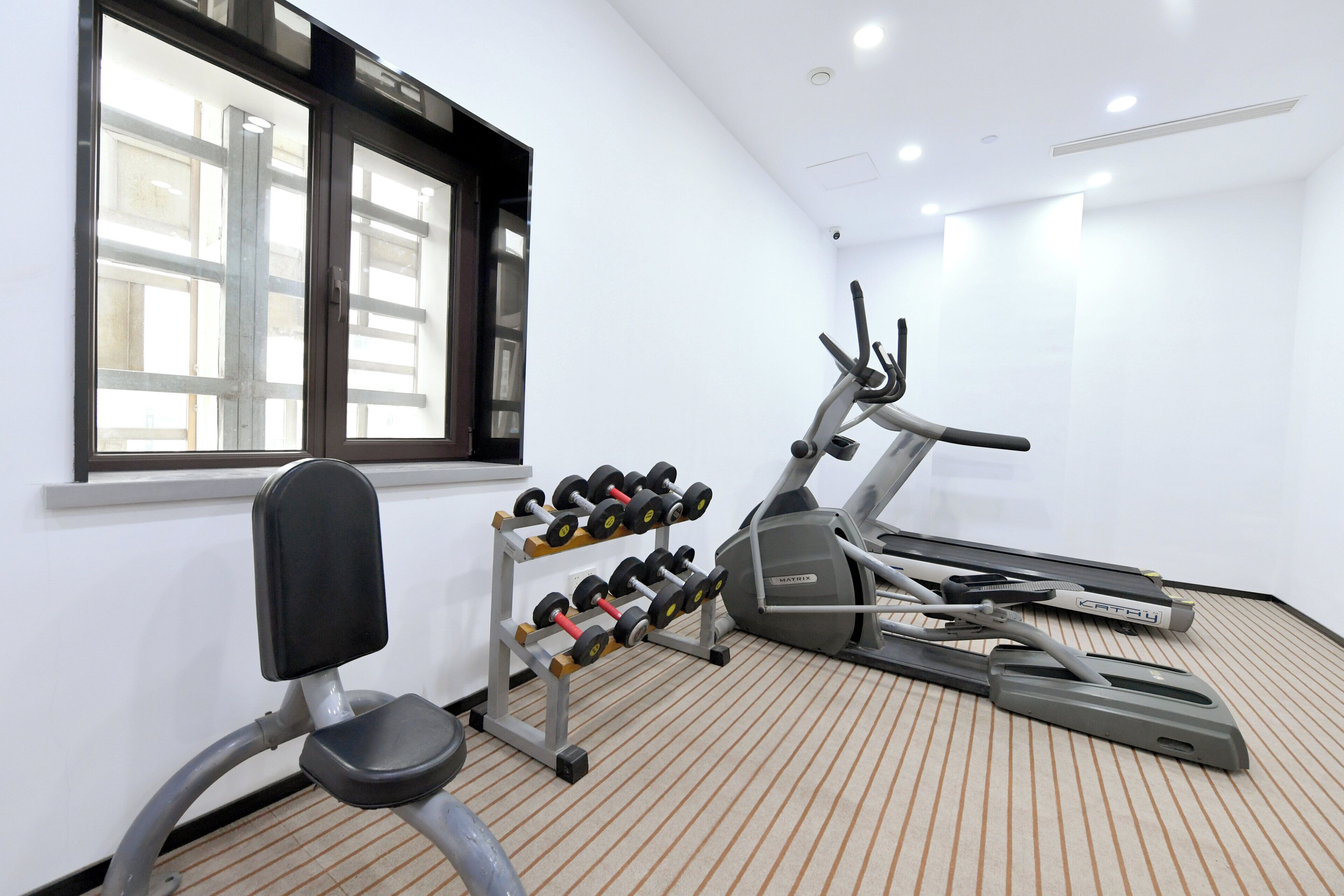 Un gimnasio con cintas de correr, una bicicleta estática y un soporte para mancuernas.