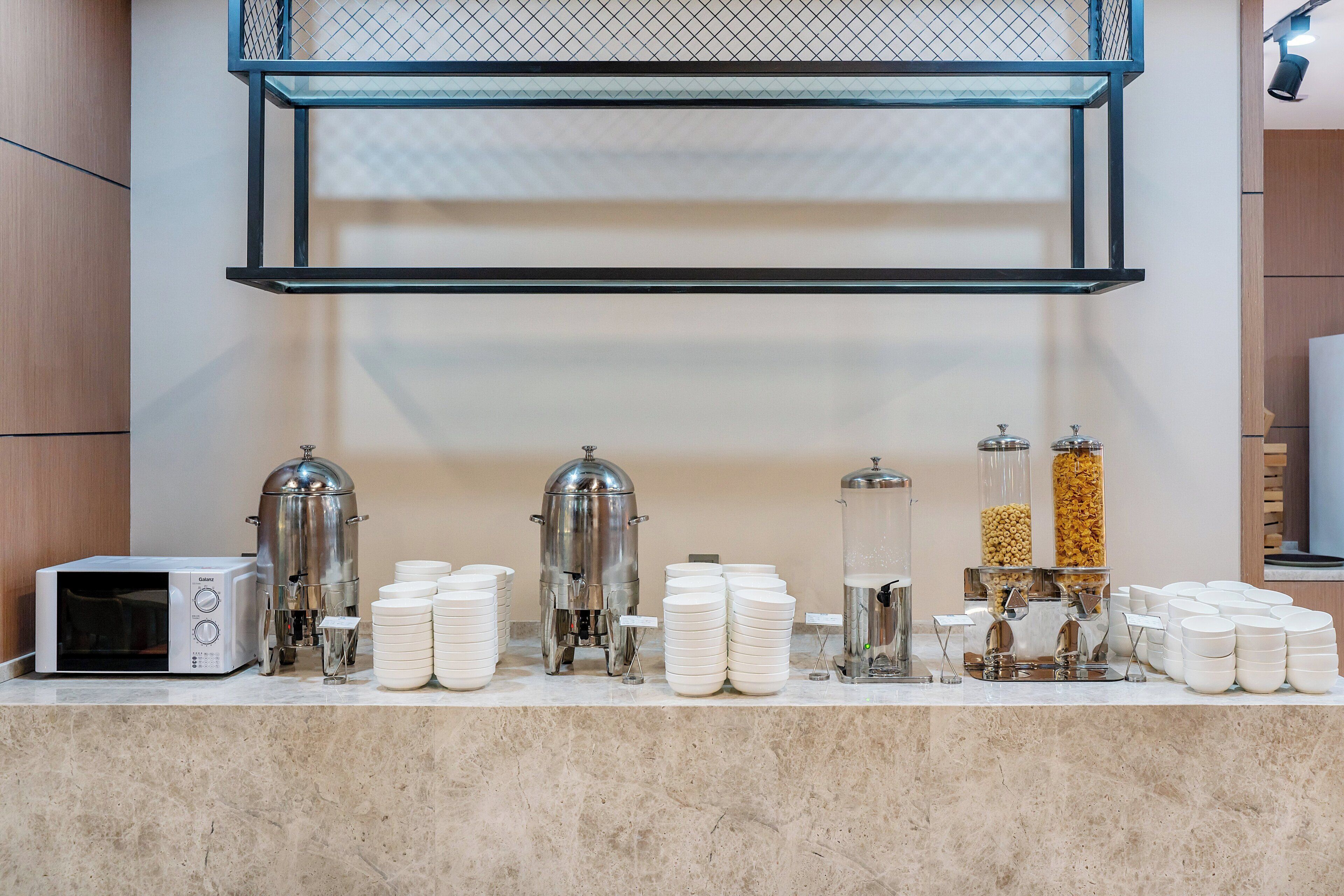 A breakfast bar with coffee machines, milk dispensers, and cereal dispensers.