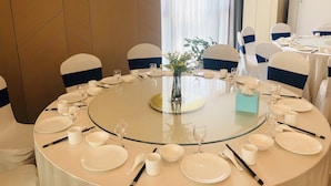 A round dining table with white tableware and chairs with blue sashes, set for a meal. - Holiday Inn Express Linyi North New District by IHG (Linyi)