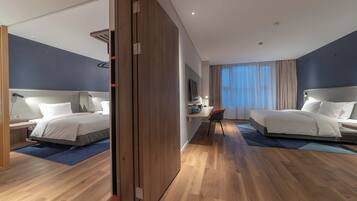 A hotel room with two beds, a desk, a chair, and a large mirror.