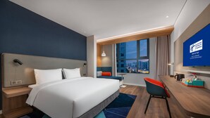 A modern hotel room with a large bed, a desk, and a view of the cityscape. - Holiday Inn Express Linyi North New District by IHG (Linyi)