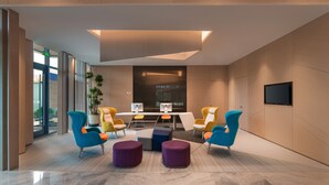 A modern conference room with a long table, colorful chairs, and a large screen. - Holiday Inn Express Linyi North New District by IHG (Linyi)