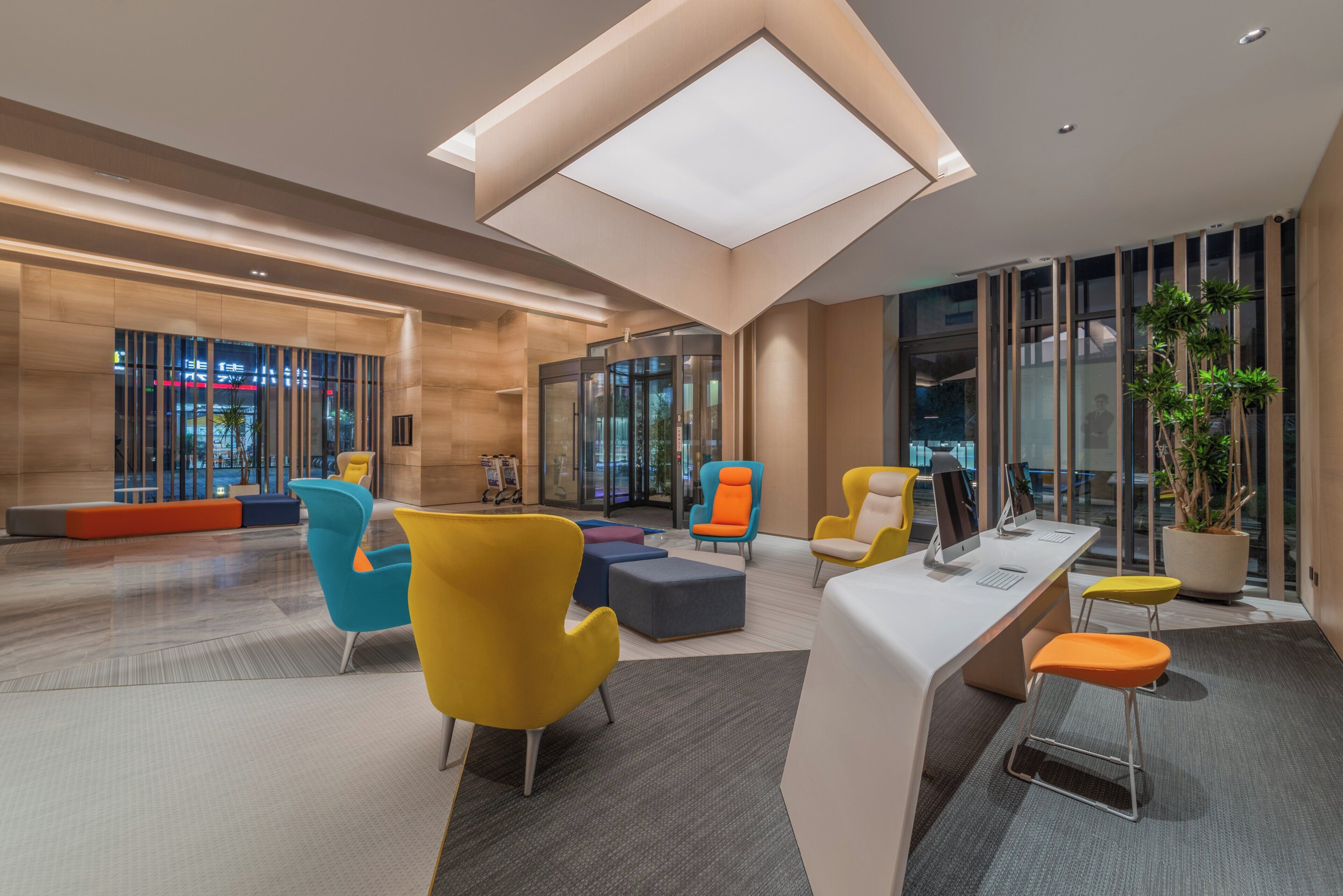 En moderne lobby med et centralt siddeområde, en receptionsdisk og en glas elevator.